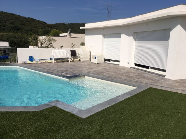 Illustration de l'intégration réussie du béton imprimé dans l'environnement - piscine, pool-house, gazon synthétique-