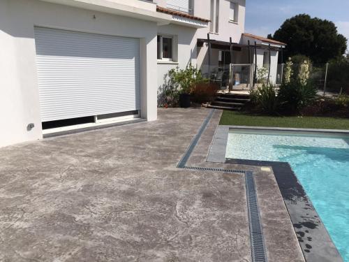 Autre vue de la terrasse terminée. Le caniveau suit les contours de la piscine pour un plus grand esthétisme.